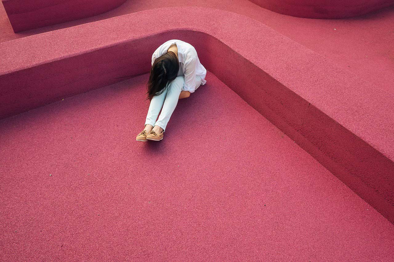 starting meditating can help relieve stress and depression. picture of a depressed person on a red floor